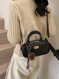 Classic black Boston handbag with glossy leather texture and fur pom-pom charm