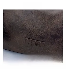 Macro shot of C&HEKA logo embossed on brown vintage leather bag with wax finish