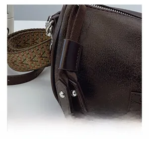 Detail of dark brown vintage pillow bag with textured leather and wide ethnic strap
