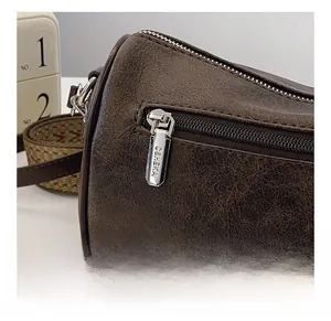 Detailed macro view of retro brown leather bag featuring branded metal zipper and woven strap