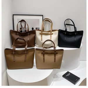 Detail view of large tote bags in five colors with textured leather on display stand