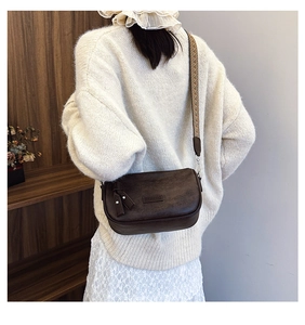 Detail of dark brown leather crossbody bag with colorful bohemian woven wide strap