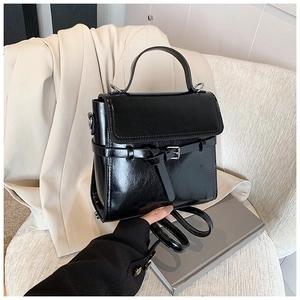 Detailaufnahme einer glänzenden schwarzen Handtasche auf einem Blazer für Damen