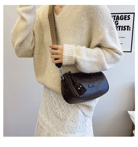 Detail of vintage dark brown cylindrical crossbody bag with geometric woven strap