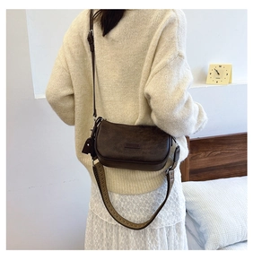 Deep brown half-moon crossbody bag with vintage woven wide strap shown on a model