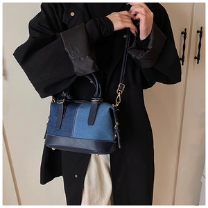 Borsa Boston alla moda in denim patchwork con manici in pelle e finiture dorate su modella