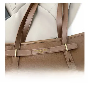 Detail of brown litchi pattern leather tote bag with gold buckle and fine stitching