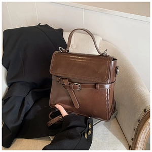 Nahaufnahme einer braunen Vintage-Handtasche mit stilvoller Schnalle auf beigem Sofa