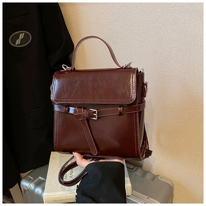 Nahaufnahme einer dunkel rotbraunen Hochglanz-Handtasche mit silberner Schnalle Detail