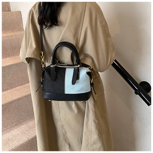 Dettaglio della borsa Boston in denim bicolore e pelle nera con finiture in metallo oro