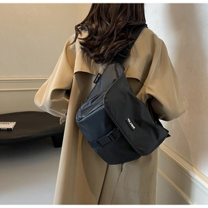Detail van de zwarte canvas crossbodytas met grote gesp en zakken met ritssluiting