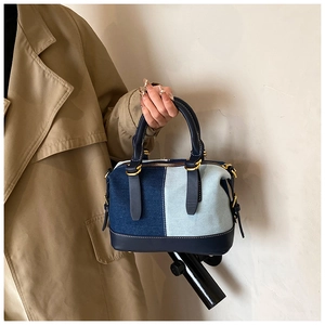 Dettaglio delle cuciture a contrasto su borsa boston patchwork di denim e oro