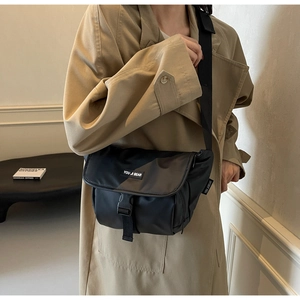 Detail van zwarte waterdichte nylon schoudertas met gesp en merklabel op het model