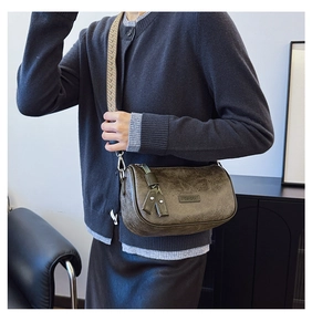Detail of vintage textured crossbody bag with patterned strap and G&REKA logo label