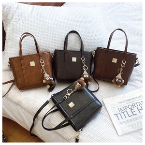 Detail view of four crossbody bags in black, coffee, tan and burgundy with plush monster charms