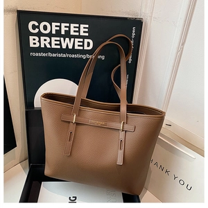 Detailed macro view of the brown lychee pattern leather and gold hardware on tote bag