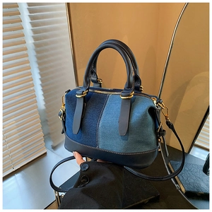 Dettaglio della borsa Boston in denim con finiture in pelle blu e accessori in metallo dorato