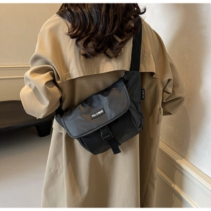 Detail van de zwarte nylon schoudertas met verstelbare brede riem en gespsluiting