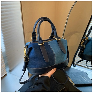 Dettaglio borsa in denim e pelle blu con cuciture bianche a contrasto e fibbie dorate