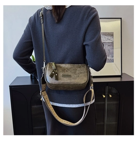 Detail of retro olive green leather bag featuring textured finish and dual strap design