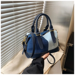 Dettaglio della borsa boston patchwork in denim con manici in pelle blu e hardware oro