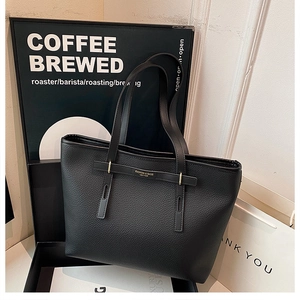 Close-up of black litchi grain leather tote bag with gold buckle and fashion logo