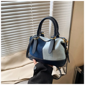 Dettaglio borsa boston patchwork in denim con finiture in pelle e fibbie dorate