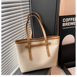 Detailed close-up of large tote bag featuring beige lychee grain leather and brown handles