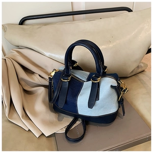 Dettaglio borsa a mano in denim patchwork con finiture dorate e bordi in pelle blu