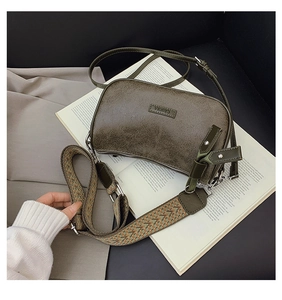 Detail of dark green pillow bag with vintage texture and stylish geometric wide strap