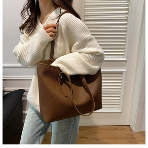 Brown leather tote bag worn by model showing large capacity and elegant side profile