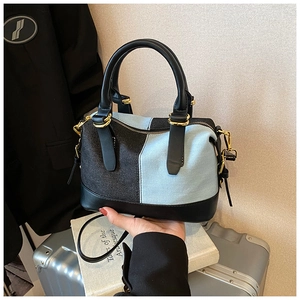 Dettaglio della borsa Boston con patchwork di denim bicolore e manici in pelle