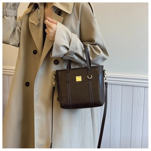 Brown tote bag with golden hardware shown with a beige trench coat for casual daily wear