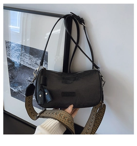 Detail of black crossbody pillow bag with brand logo and ethnic woven shoulder strap