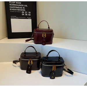 Three retro box bags in burgundy, coffee and black on a white tiered display stand