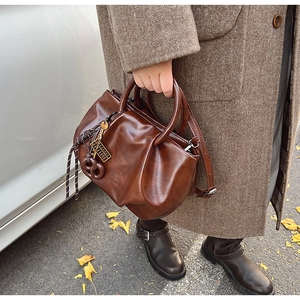 Détails du sac seau plissé marron vintage avec pendentif décoratif et bandoulière