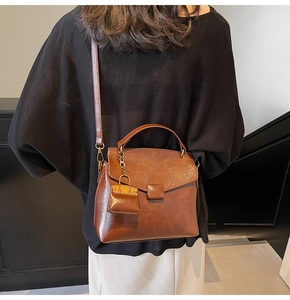 Detail of dark brown vintage faux leather underarm bag with decorative mini bag charm
