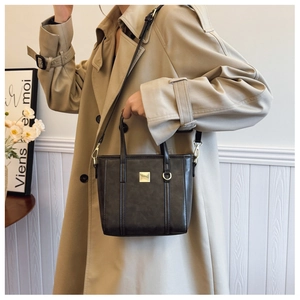 Detail showing the dark brown leather texture, gold metal buckle, and sturdy handles