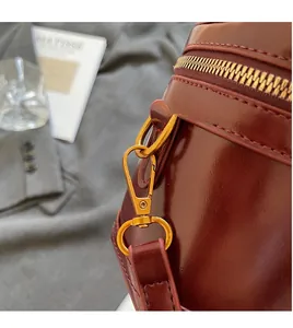 Close-up of golden metal lobster clasp and shiny burgundy patent leather box bag