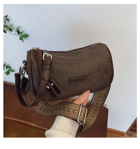 Detail of dark brown cylindrical pillow bag featuring a wide ethnic woven strap