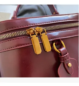 Close-up of smooth dual zippers and gold hardware on burgundy leather box bag