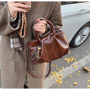 Détail du sac seau en cuir plissé marron foncé avec breloques et bandoulière amovible