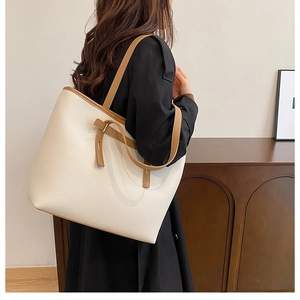 Close-up of cream leather tote bag with brown straps and textured lychee grain finish