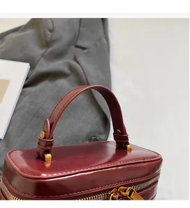 Close-up of a burgundy leather handbag with premium gold metal handle and zipper details