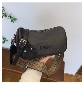 Close-up of black retro pillow bag with textured leather and geometric wide woven strap