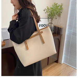 Detail of beige tote bag with pebbled leather texture and brown shoulder strap on model