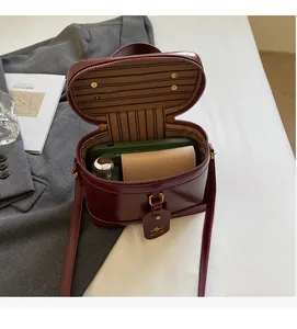 Interior detail of a dark red cylinder bag showing striped lining and zipper closure