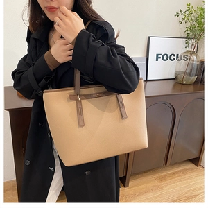 Beige faux leather large tote bag with brown straps styled on a black long coat