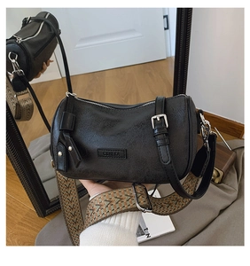 Detail of black cylinder bag with geometric woven strap and silver hardware accents