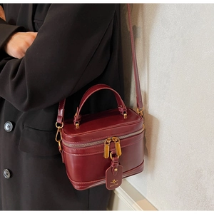 Detail of wine red box bag with gold-tone dual zippers and MICHTAM logo tag